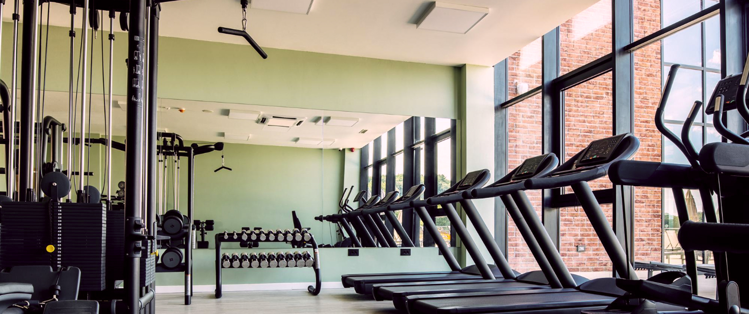 Тренажерный зал с панорамными окнами с большим количеством различных тренажеров